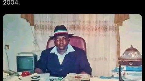 A man in a hat at his office desk, in a photograph dated 2004